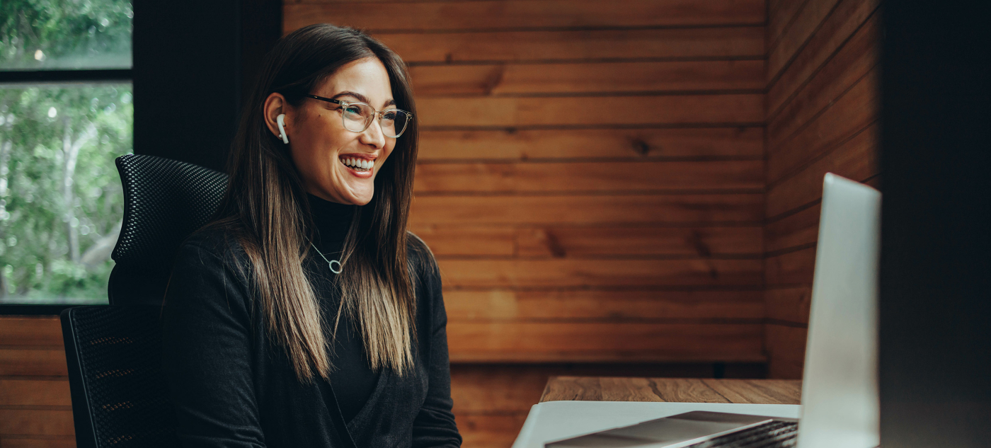 A person sits at a desk, smiling in front of a computer.