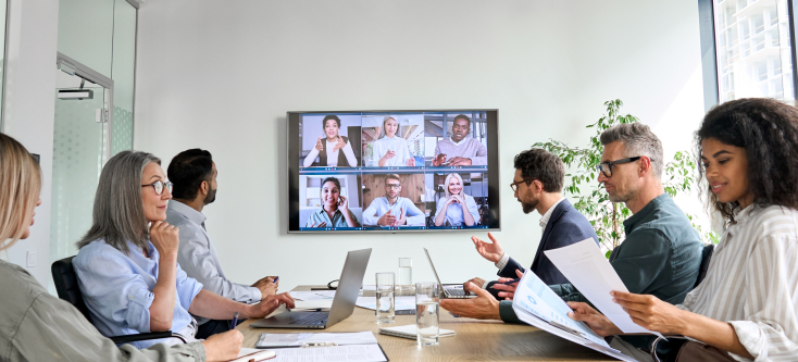 A group of people participate in a hybrid meeting.